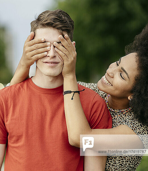 Young woman covering boyfriend's eyes