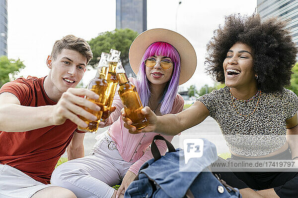 Multi-ethnic male and female friends celebrating while sitting at park