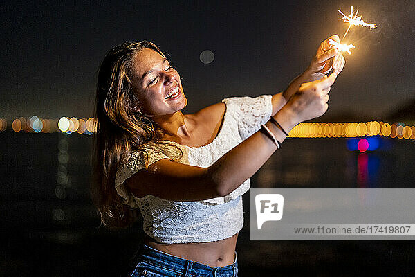 Cheerful young woman enjoying with sparklers at night