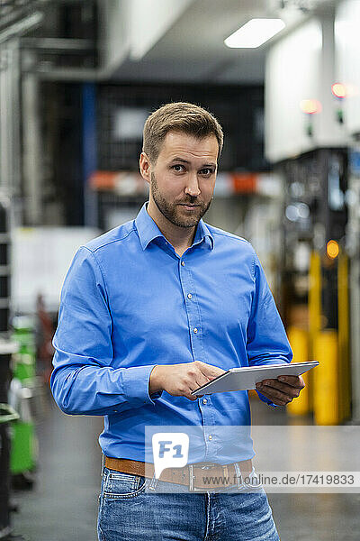 Male professional with digital tablet standing at industry