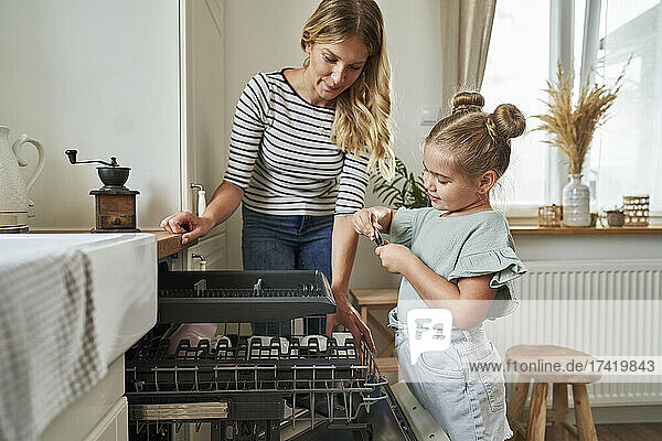 Frau und Mädchen stehen neben der Spülmaschine in der Küche