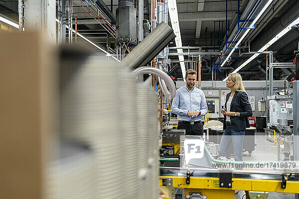 Female manager standing with male coworker at production line