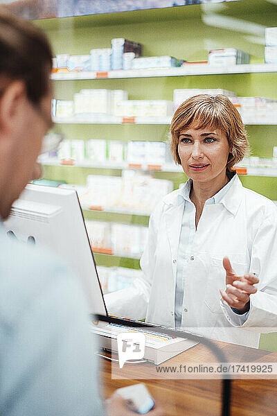 Female pharmacist talking to customer at pharmacy