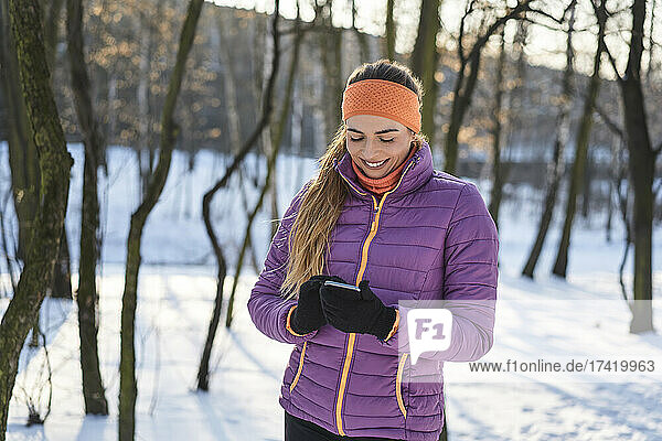 Woman in padded jacket using smart phone during winter