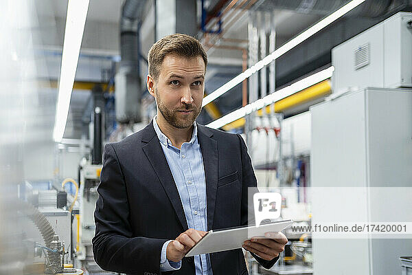 Thoughtful male professional with digital tablet at industry