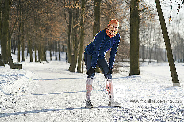 Smiling woman taking break while exercising during winter