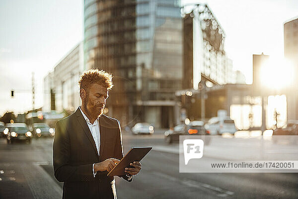Mature businessman using digital tablet on street