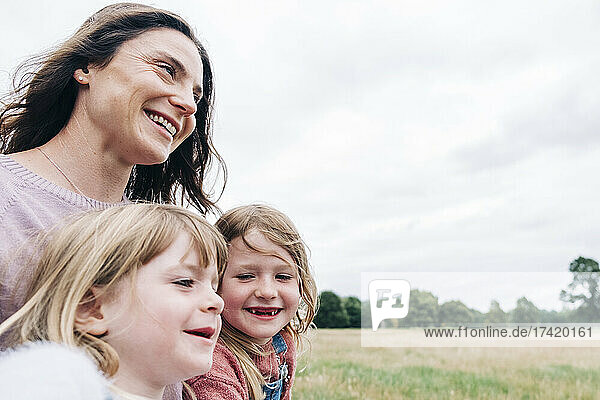 Mother with smiling daughters at meadow