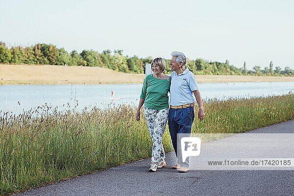 Smiling senior couple walking with arm around on road