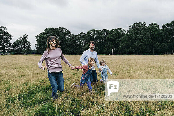 Playful family running on meadow during vacation