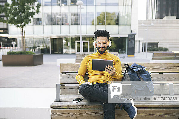 Man watching video through digital tablet while sitting on bench