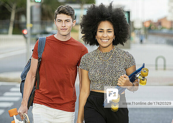 Young couple walking while holding skateboards