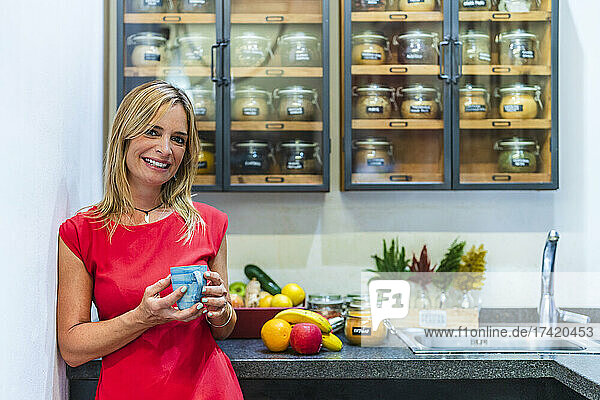 Smiling woman holding mug of tea at store