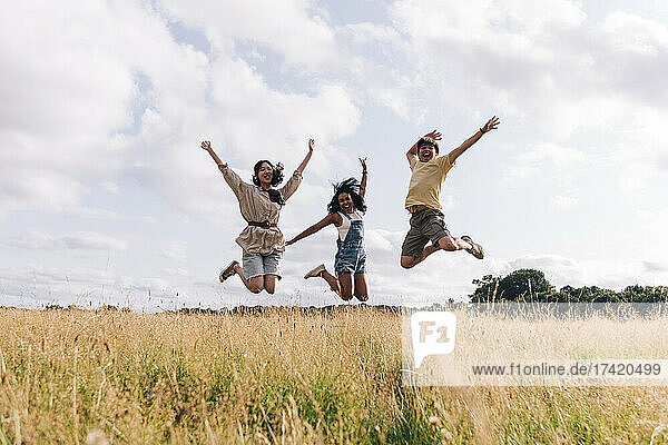 Happy friends enjoying while jumping on meadow