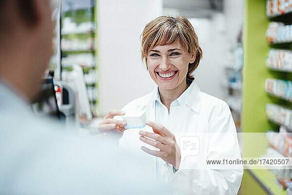 Smiling female pharmacist discussing with male customer at pharmacy store