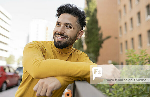 Smiling handsome bearded man leaning on railing