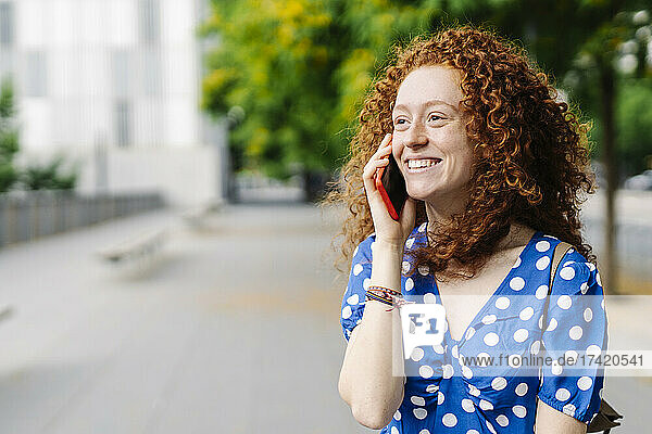 Smiling redhead woman talking on mobile phone