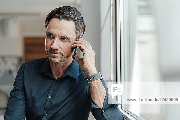 Mature businessman talking on smart phone at work place