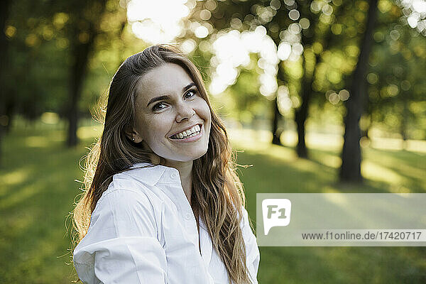 Beautiful woman with brown hair smiling at park