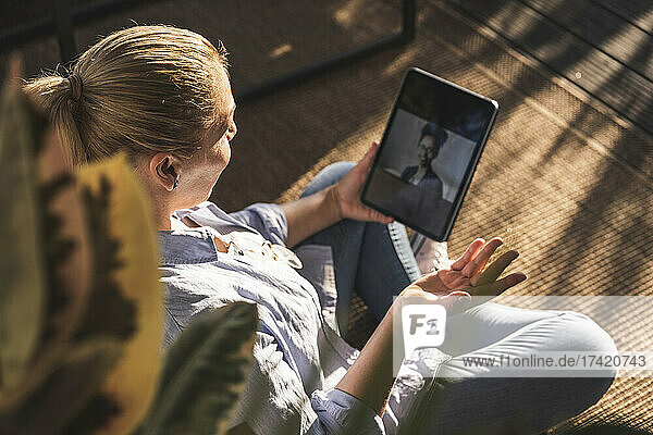 Woman talking with friend on video call through digital tablet on terrace