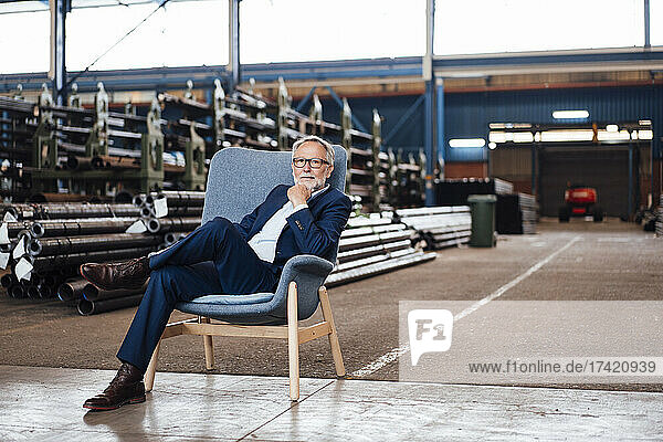 Senior businessman sitting on armchair in industry