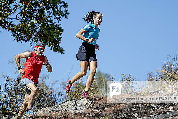 Mature male coach running with female athlete during sunny day