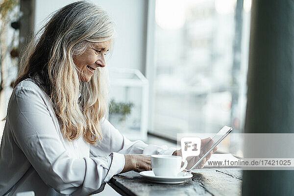 Female freelancer using digital tablet while sitting in cafe