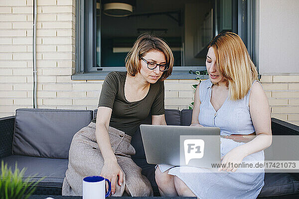 Female professionals using laptop while sitting on sofa