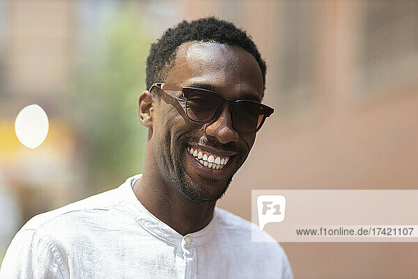 Young man in sunglasses smiling during day