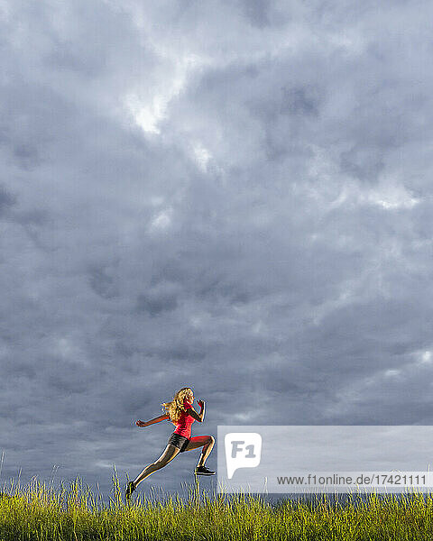Young woman running against cloudy sky