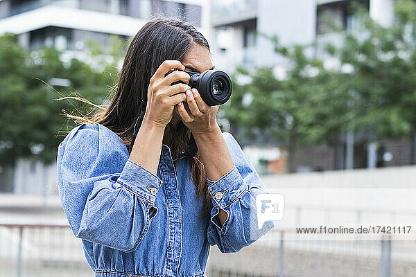 Female freelancer photographing through camera in city