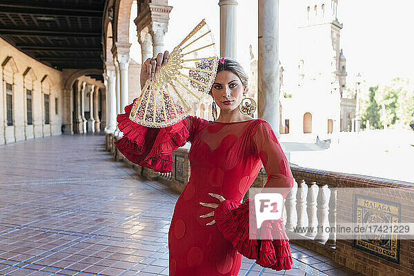 Woman wearing traditional dress holding hand fan at Plaza De Espana walkway in Seville  Spain