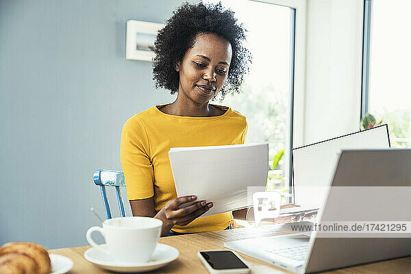 Businesswoman reading documents at home office