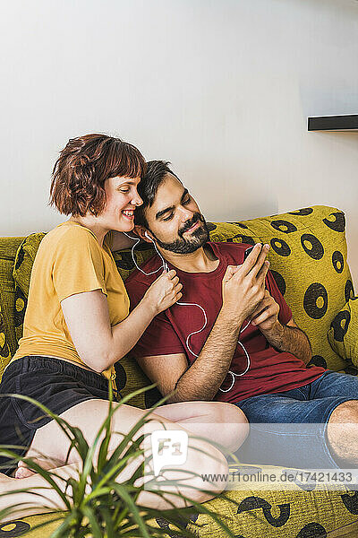 Young man showing mobile phone to girlfriend on sofa