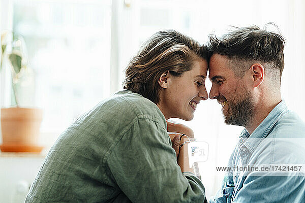 Happy man and woman touching foreheads at home