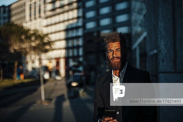 Mature businessman with mobile phone during sunny day