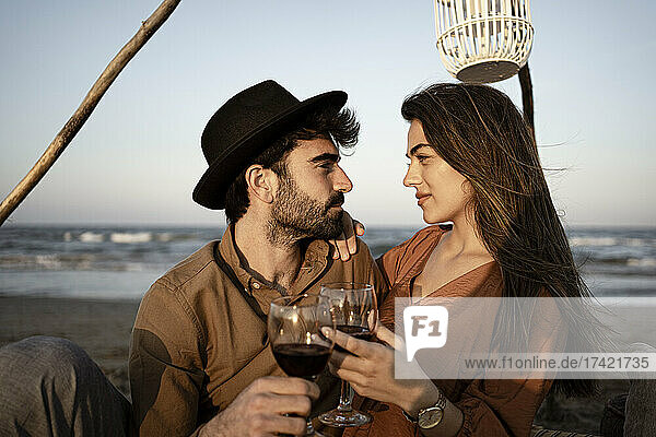 Couple looking at each other while holding drinks during picnic