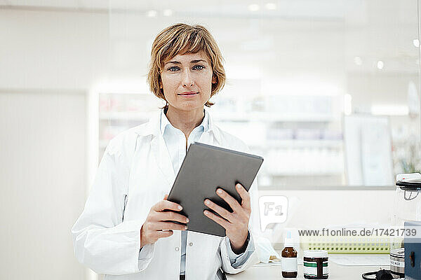 Female pharmacist with digital tablet standing in pharmacy