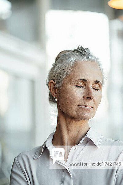 Mature woman with eyes closed in cafe