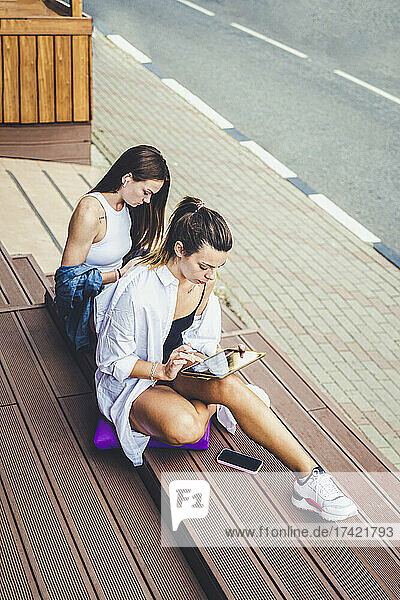 Businesswoman using digital tablet while telecommuting by female colleague on bench