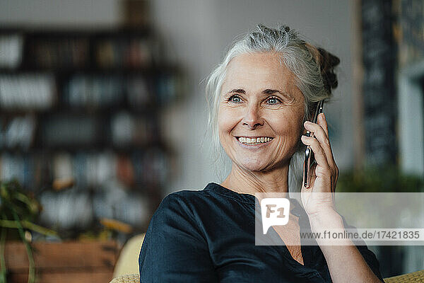 Smiling female freelancer talking on mobile phone in cafe