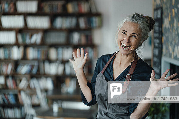 Cheerful female cafe owner gesturing with mouth open in coffee shop