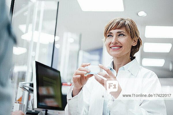 Smiling female pharmacist discussing over medicine with male customer at pharmacy store