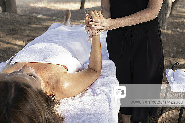 Weibliche Massagetherapeutin massiert die Hand des Kunden im Spa