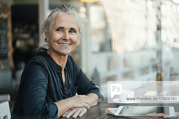 Smiling businesswoman sitting at table in cafe