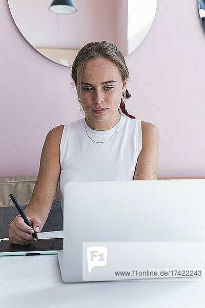 Young female design professional using graphic tablet while sitting in cafe