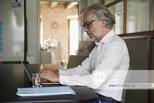 Mature businessman working on laptop at desk in office
