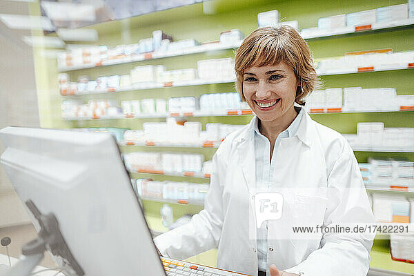 Happy female pharmacist standing in store
