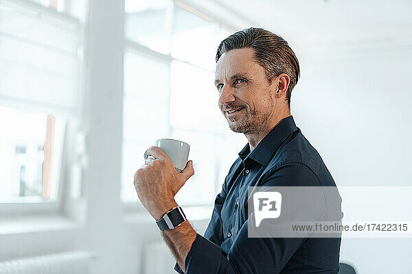 Thoughtful businessman having coffee at work place