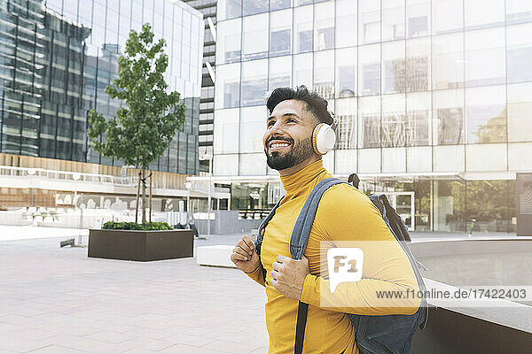 Smiling man with headphones and backpack in city